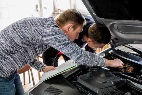 Zwei Auszubildende betrachten zusammen den Motor eines Elektroautos.